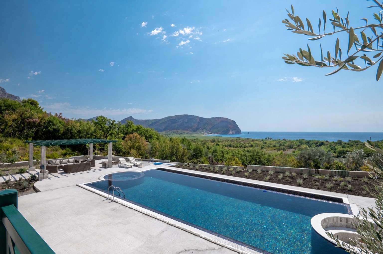 Piscine à débordement surplombant la mer Adriatique, encadrée par une branche d'olivier, à Paštrovići Stone Retreat
