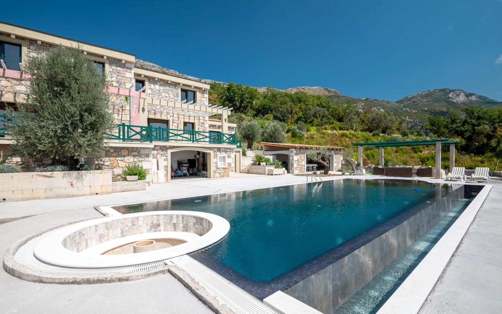 Vue large de la piscine et de la façade en pierre à Paštrovići Stone Retreat
